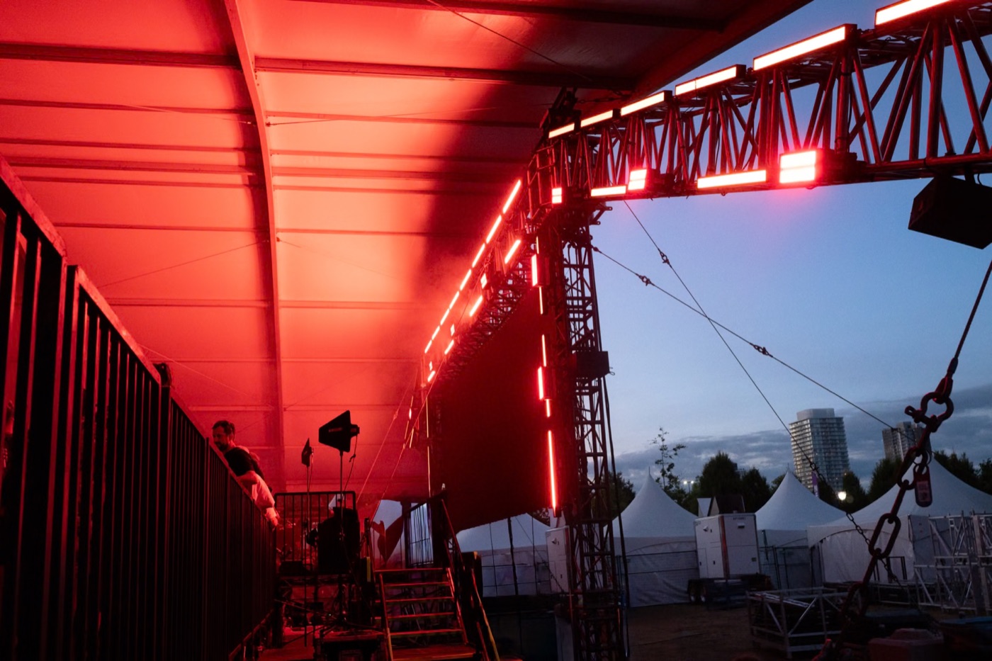 a stage truss glowing red against a blue evening sky